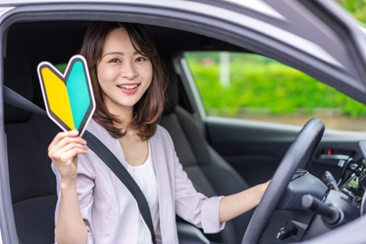 初心者マークを持って運転席に座る女性